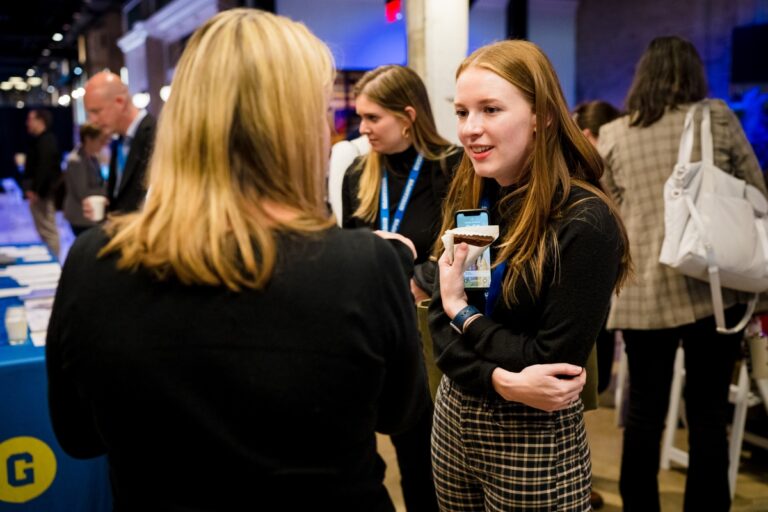Women chatting in a crowded room at a networking event.