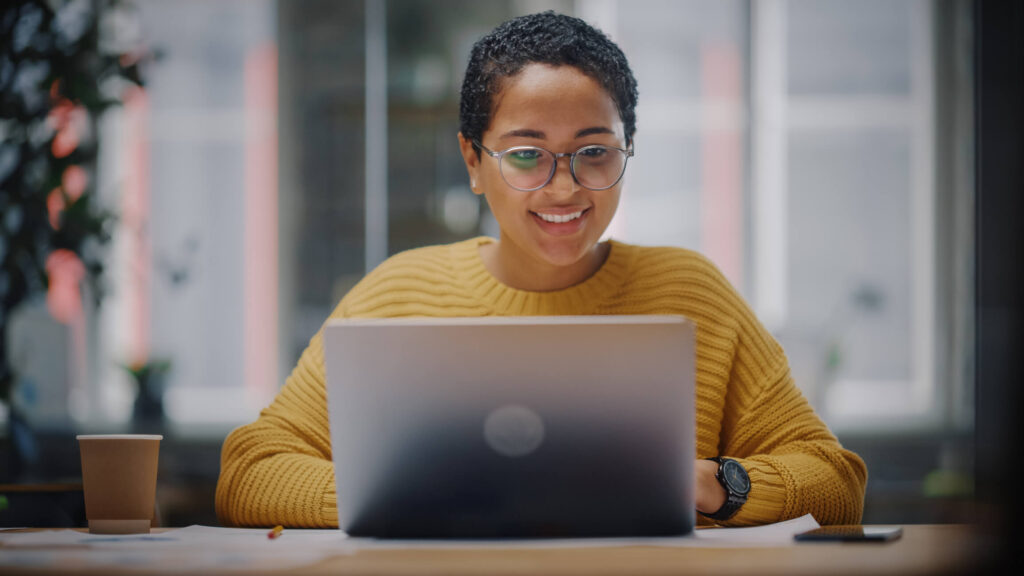 Smiling woman at laptop answering email inquiry to support desk.