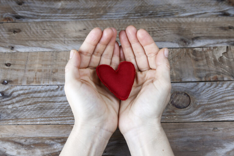 Red heart handmade on the hands of a woman