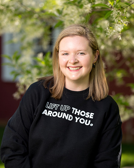 GiveCampus employee wearing a values sweatshirt that says, "Lead with curiosity and empathy."