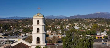A church steeple and buildings on a green hillside