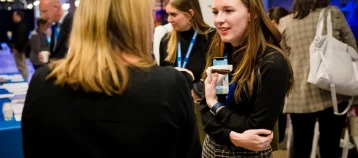 Women chatting in a crowded room at a networking event.