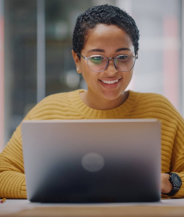 Smiling woman at laptop answering email inquiry to support desk.