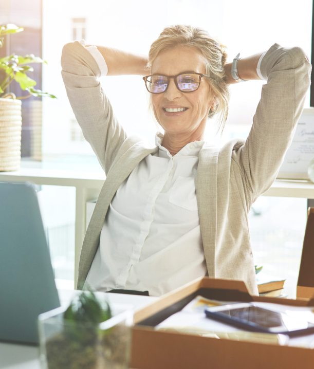 Business woman feeling accomplished and enjoying a relaxing break to stretch with hands behind her head in an office.