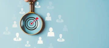 Magnifying glass over bulls-eye in a crowd of people.