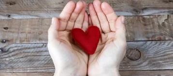 Red heart handmade on the hands of a woman