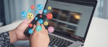 Engagement and emoji reactions coming out of an iphone that is showing a social media feed