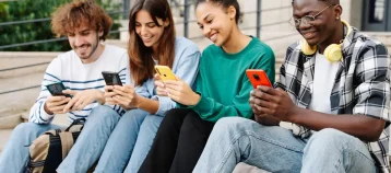 young alumni sitting on steps on their phones
